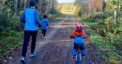 Perhe lenkkeilemässä syksyisessä luonnossa.