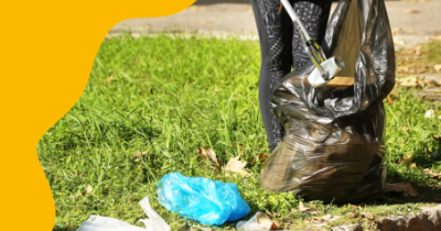 Henkilö kerää ulkona roskia säkkiin