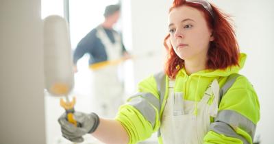 Kuvassa tyttö maalaa seinää