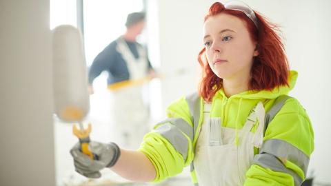 Kuvassa tyttö maalaa seinää